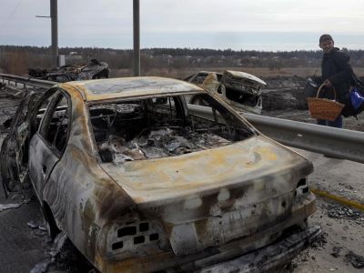 Житель Ирпени около сгоревших в результате обстрела автомобилей, 12 марта 2022 года. Фото: Ефрем Лукацкий / AP Photo